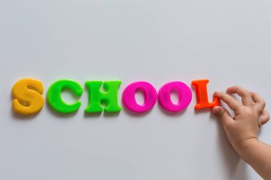 Okul kelimesi bir çocuğun el yazısıyla yazılmış renkli manyetik harflerden yapılmıştır. Çocuğun erken gelişimi.