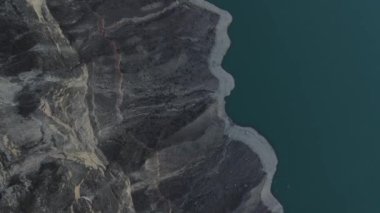 Zümrüt renkli suyla bir dağ rezervuarının kayalık kıyısında uçmak. Hava videosu. Üst Manzara. Irganai rezervuarı, Dağıstan, Rusya.