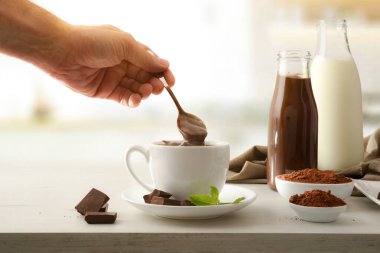 Mutfak tezgahında yeni hazırlanmış sıcak çikolata, porsiyonlar ve pudralanmış çikolata ve süt şişeleri ve mutfakta sıvı çikolata.. 