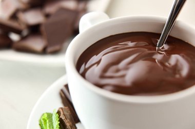 Tabakta beyaz seramik bardakta sıcak çikolata ve beyaz ahşap masada nane yaprakları. Manzara yükseldi. Yatay bileşim.