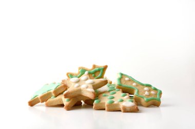 Beyaz masadaki yığının içinde beyaz ve yeşil kremayla süslenmiş Noel şekilli kurabiyeler. Ön manzara. Yatay bileşim.