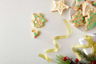 Noel kurabiyeleriyle süslenmiş bir tabak şeker ve Noel süsüsüyle beyaz masada. Üst Manzara. Yatay bileşim.