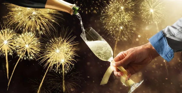 Fyllning Champagneglas Prydd Med Guldbåge Från Flaska Med Fyrverkeribakgrund Fest — Stockfoto