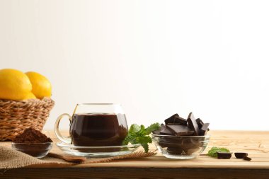 Tahta sehpanın üzerinde cam bardakta organik sıcak çikolata ve izole edilmiş beyaz çikolata tozu. Ön manzara. Yatay bileşim.