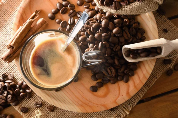 木制底座上的一杯热咖啡和肉桂 以及平底锅上的咖啡豆 顶部视图 横向构成 — 图库照片