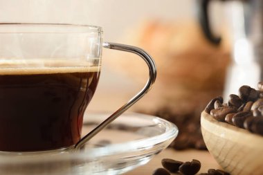 Tahta masa makro manzaralı bir bardak sıcak kahve ve kahve çekirdeği. Ön manzara. Yatay bileşim.