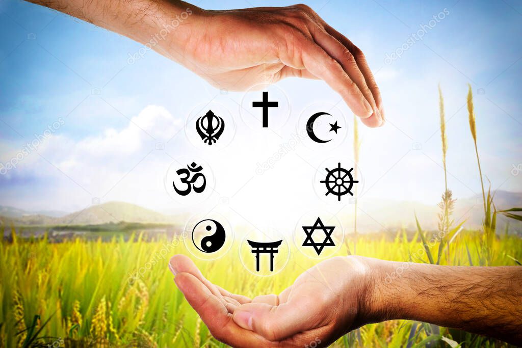 Hands encompassing symbols of the most representative religions with a nature background. Horizontal composition.