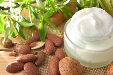 Nemlendirici krem, doğadaki ahşap masanın üzerinde badem özü. Manzara yükseldi. Yatay bileşim.