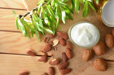 Nemlendirici krem, doğadaki ahşap masanın üzerinde badem özü. Üst Manzara. Yatay bileşim.