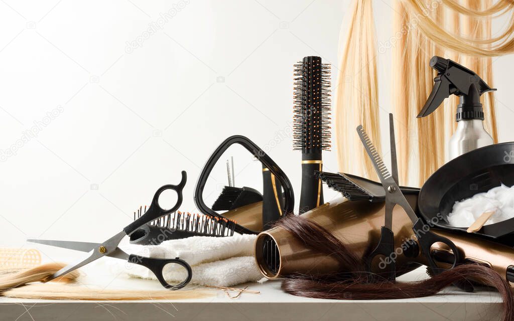 Hairdressing tools on table with hair extensions in the background. Front view. Horizontal composition.
