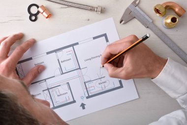 Ofis masasında bir ev suyu kurulumunun tasarımını inceleyen teknisyen. Üst Manzara. Yatay bileşim.