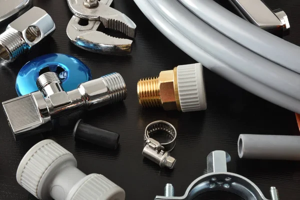 Siyah tezgahtaki tesisat malzemeleri ve aletlerin ayrıntıları. Manzara yükseldi. Yatay bileşim.