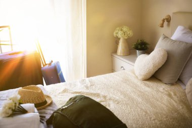 Bright and sunny vacation hotel room with suitcases and hand luggage and sunbeam coming through the window