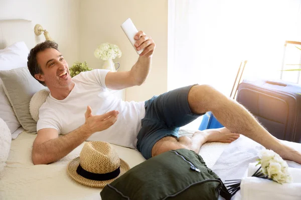 Happy Man Vacation Taking Selfie Lying Bed Hotel Room — Stock Fotó