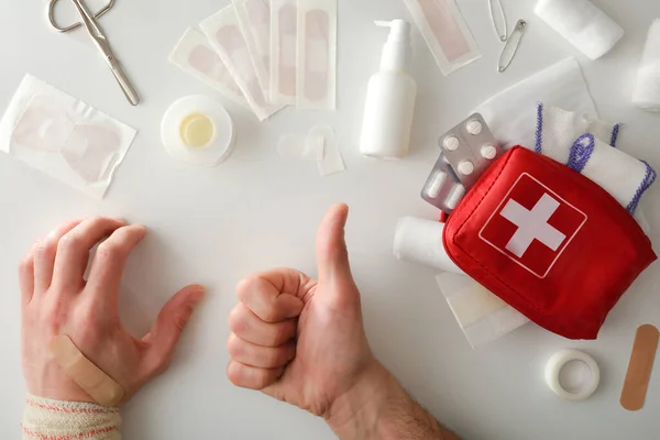 Heal successfully with portable first aid equipment on the table and hand with ok gesture and bandaged hand. Horizontal composition. Top view.