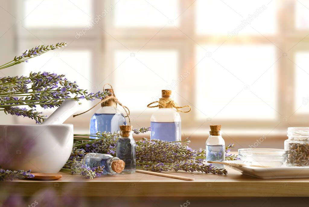 Natural essences freshly prepared at home on wooden table with spikes around and window background. Front view. Horizontal composition.