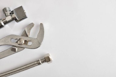Boru tesisatı, İngiliz anahtarı, hortum ve papağan burunlu pense beyaz masada. Üst Manzara. Yatay bileşim.
