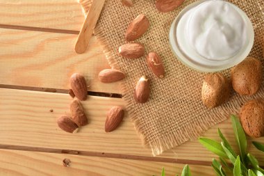 Nemlendirici krem, doğadaki ahşap masanın üzerinde badem özü. Üst Manzara. Yatay bileşim.