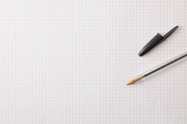Teaching and education background with pen on checkered paper. Top view.