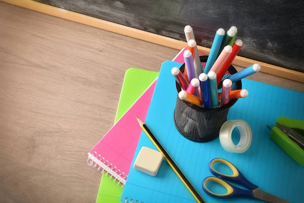School Supplies Pen Markers Notebooks Tools Wooden Desk Blackboard Elevated — Stockfoto