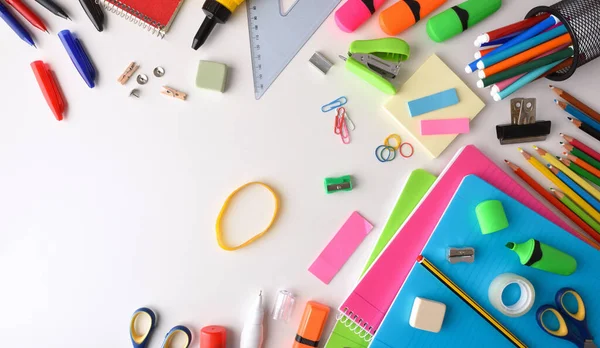 Assortment of colorful school supplies on white desk. Top view. Horizontal composition.