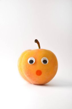 Healthy peach with face on white isolated background. Fruits and vegetables child healthy eating concept