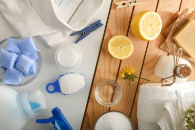 Detail comparison of ecological laundry cleaning products on wooden table and chemicals on white table. Top view. Horizontal composition.