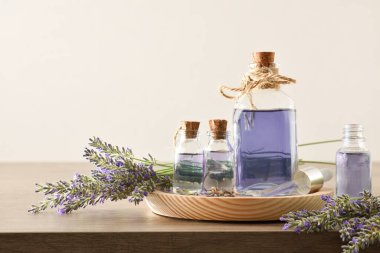 Natural perfume with lavender essence background in bottles and bouquets of spikes around on wooden table and white isolated background. Front view. Horizontal composition.