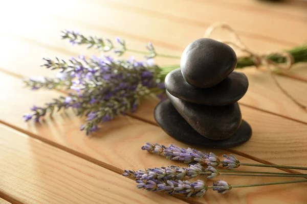 Balance and health concept with pile of black stones on wood and spikes of flowering lavender. Top elevated view. Horizontal composition.