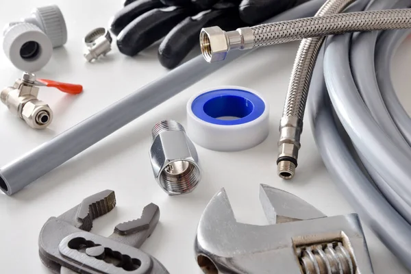 Group of plumbing materials and tools on white workbench. Elevated view. Horizontal composition.