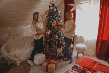 Mutlu aile, Noel ağacını bıldırcın ve hediyelerle süslüyor oturma odasında, Mutlu Noeller ve yeni yıl tatilleri. Aile, kış tatili ve insanlar konsepti.