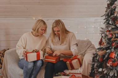 Mutlu kadın anneler Noel için hazırlanıyor, yeni yıl hediyeleri evde Noel ağacının yanında otururken paketleniyor. Kış tatili, ev dekorasyonu konsepti