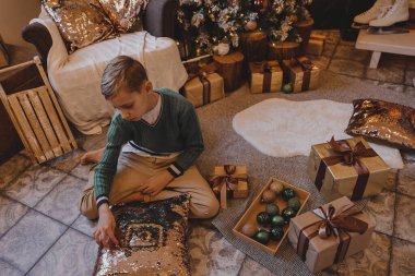 Çocuk Noel ağacını evde süslüyor. Çocuklu aile kış tatilini kutlar. Çocuklar Noel için oturma odasını ve şömineyi dekore ederler..