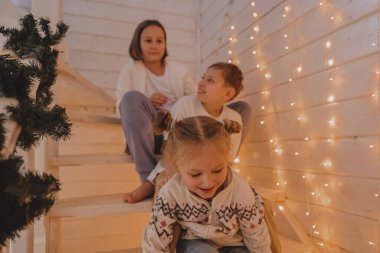 Çocuklar yılbaşı süslemeli evlerinde, ailelerinde, kış tatillerinde ve insanların konseptinde Noel süslemeli merdivenlerde oynarlar.