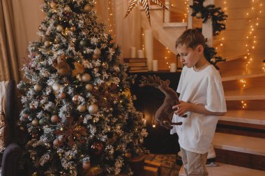Çocuk Noel ağacını evde süslüyor. Çocuklu aile kış tatilini kutlar. Çocuklar Noel için oturma odasını ve şömineyi dekore ederler..