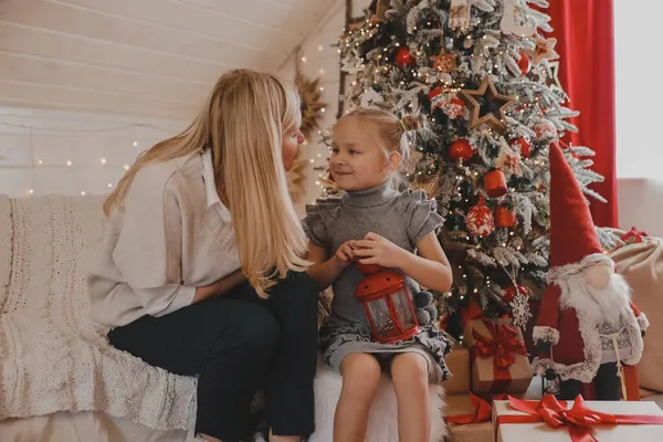 Mutlu anne ve küçük kızı evde Noel ağacı süslüyorlar. Aile, kış tatili ve insanlar konsepti.