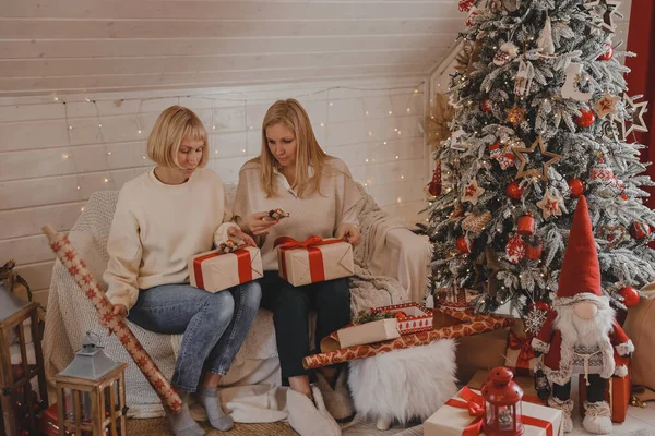 Mutlu kadın anneler Noel için hazırlanıyor, yeni yıl hediyeleri evde Noel ağacının yanında otururken paketleniyor. Kış tatili, ev dekorasyonu konsepti
