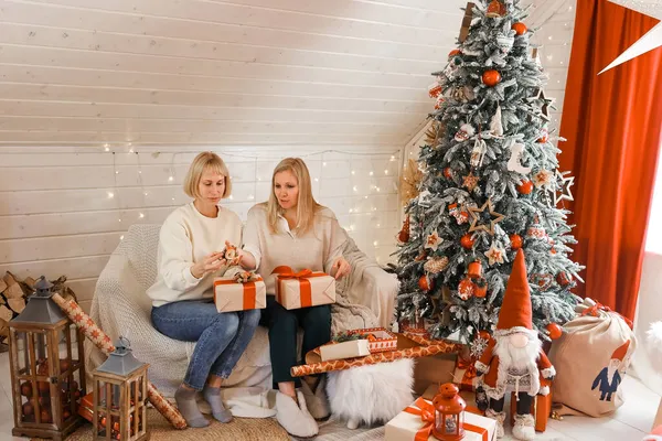 Mutlu kadın anneler Noel için hazırlanıyor, yeni yıl hediyeleri evde Noel ağacının yanında otururken paketleniyor. Kış tatili, ev dekorasyonu konsepti