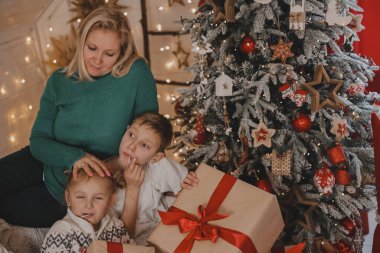 Morher ve Çocuklar yılbaşı atmosferinde. Aile Noel ve hediyelerle mutlu. Çocuklar yılbaşı ağacında hediyelerle.