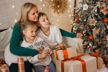 Morher ve Çocuklar yılbaşı atmosferinde. Aile Noel ve hediyelerle mutlu. Çocuklar yılbaşı ağacında hediyelerle.