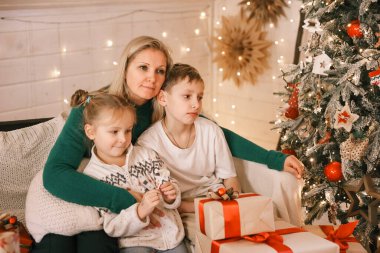 Morher ve Çocuklar yılbaşı atmosferinde. Aile Noel ve hediyelerle mutlu. Çocuklar yılbaşı ağacında hediyelerle.