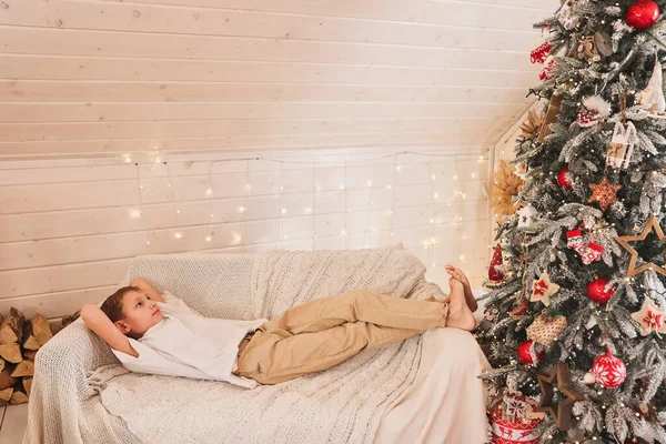 Lindo Chico Encuentra Sofá Junto Árbol Navidad Habitación Decorada Año — Foto de Stock