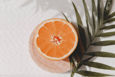 Orange fruit and a green palm leaf on white background. Summer wedding mock-up invitation. Top view, flat lay, copy space.