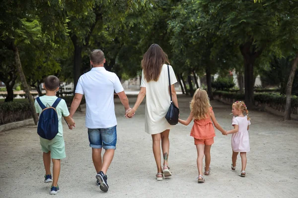 Family spending time together, cheerful parent with kids walking in the park in good weather