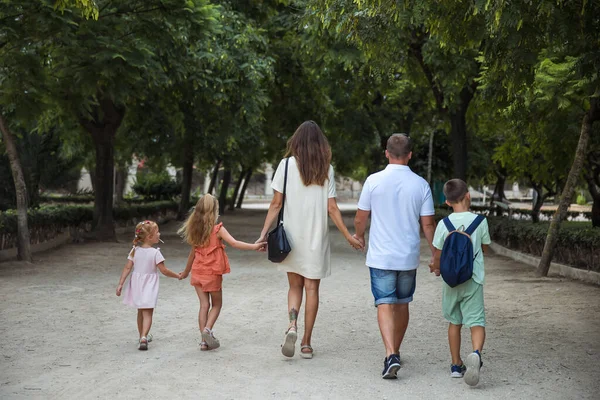 Family spending time together, cheerful parent with kids walking in the park in good weather