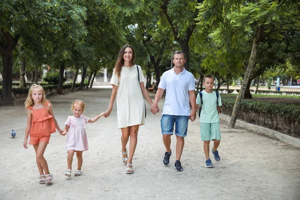 Family spending time together, cheerful parent with kids walking in the park in good weather