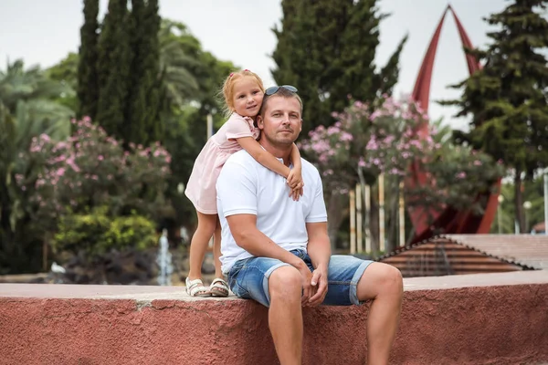 Dad walks with his daughter in a city park, a little girl hugs her father, a family pastime