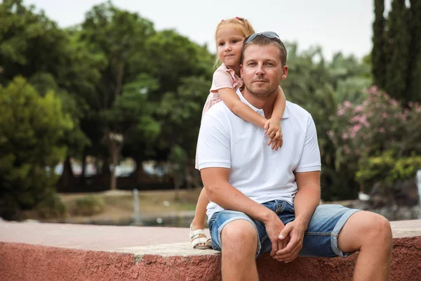 Dad walks with his daughter in a city park, a little girl hugs her father, a family pastime