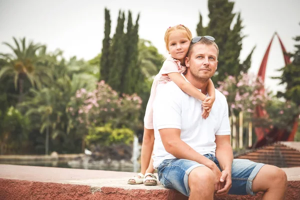 Dad walks with his daughter in a city park, a little girl hugs her father, a family pastime