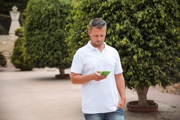 A man talks on a mobile phone in a city park, a businessman in nature, work in the fresh air